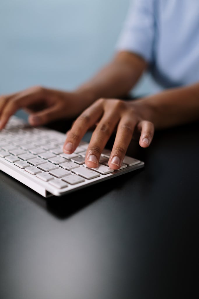 What To Do When You Can’t Write 1 A close-up view of hands typing on a sleek white wireless keyboard on a desk.