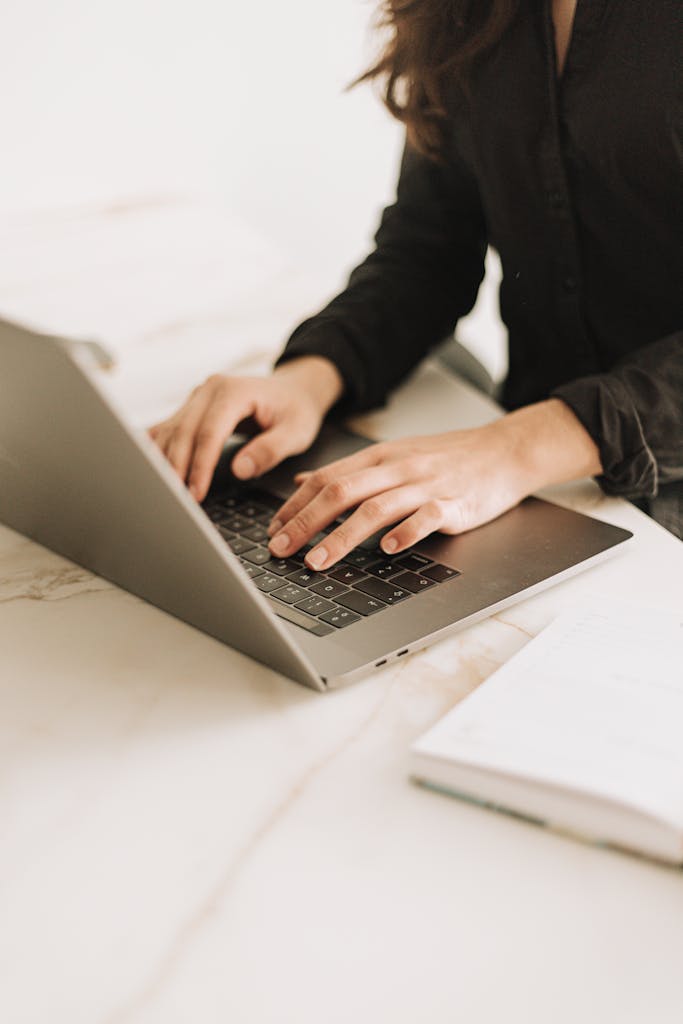 What To Do When You Can’t Write 2 Woman typing on laptop in bright, modern workspace. Ideal for business settings.